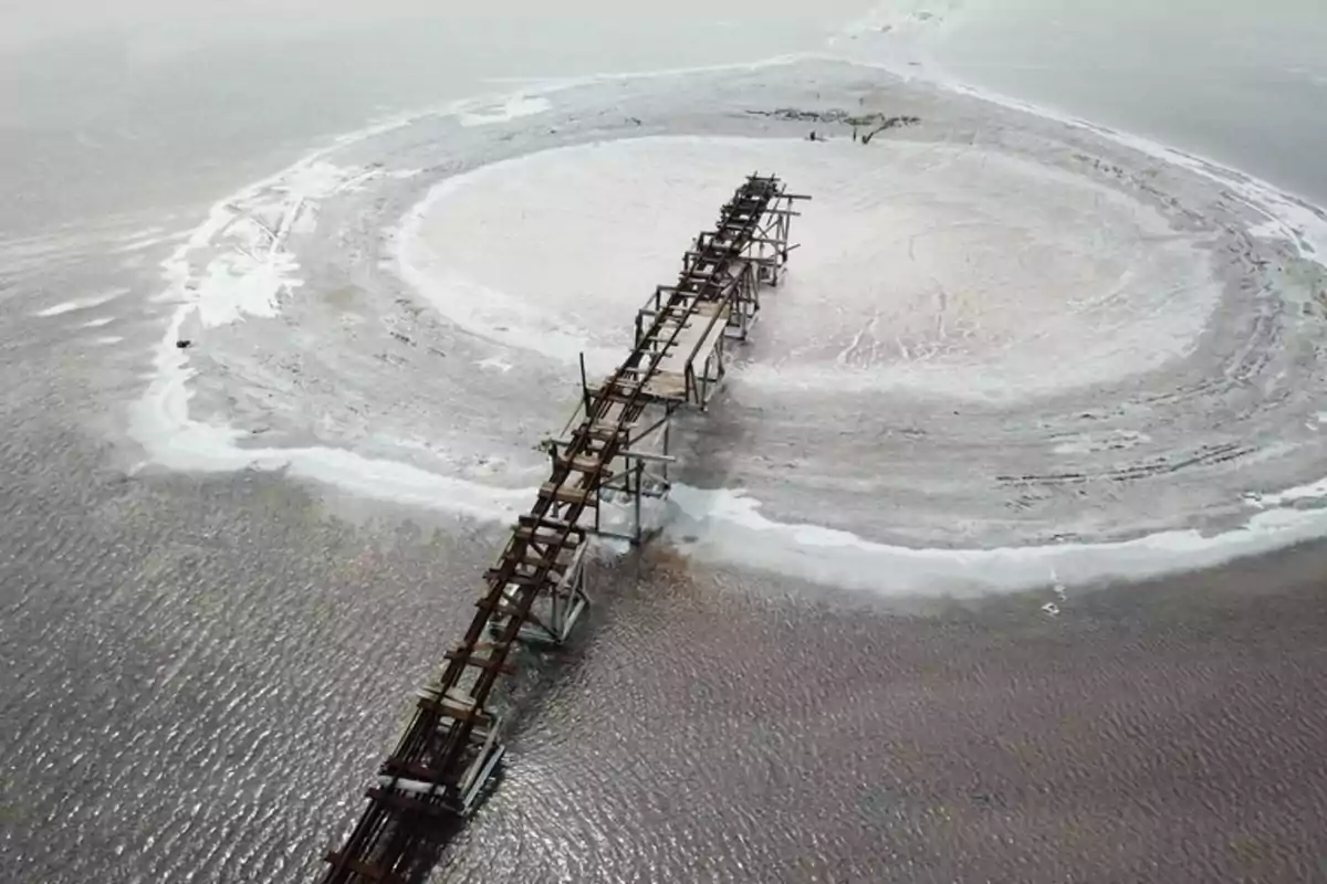 Estructura de madera y metal en ruinas sobre una superficie salina con un círculo blanco en el centro del paisaje árido Estructura de madera y metal en ruinas sobre una superficie salina con un círculo blanco en el centro del paisaje árido