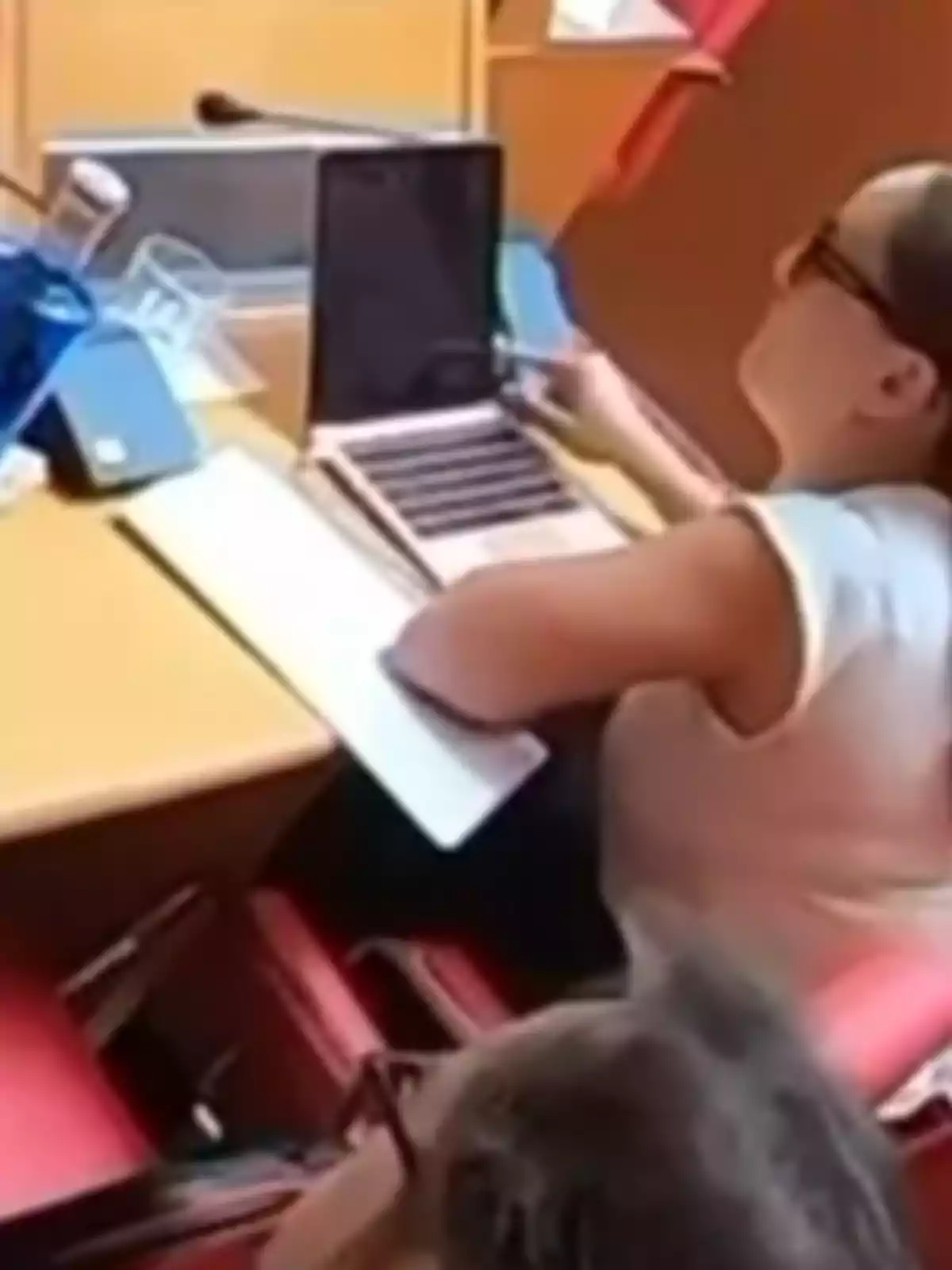 Mujer con gafas usando una laptop en una mesa de trabajo Mujer con gafas usando una laptop en una mesa de trabajo
