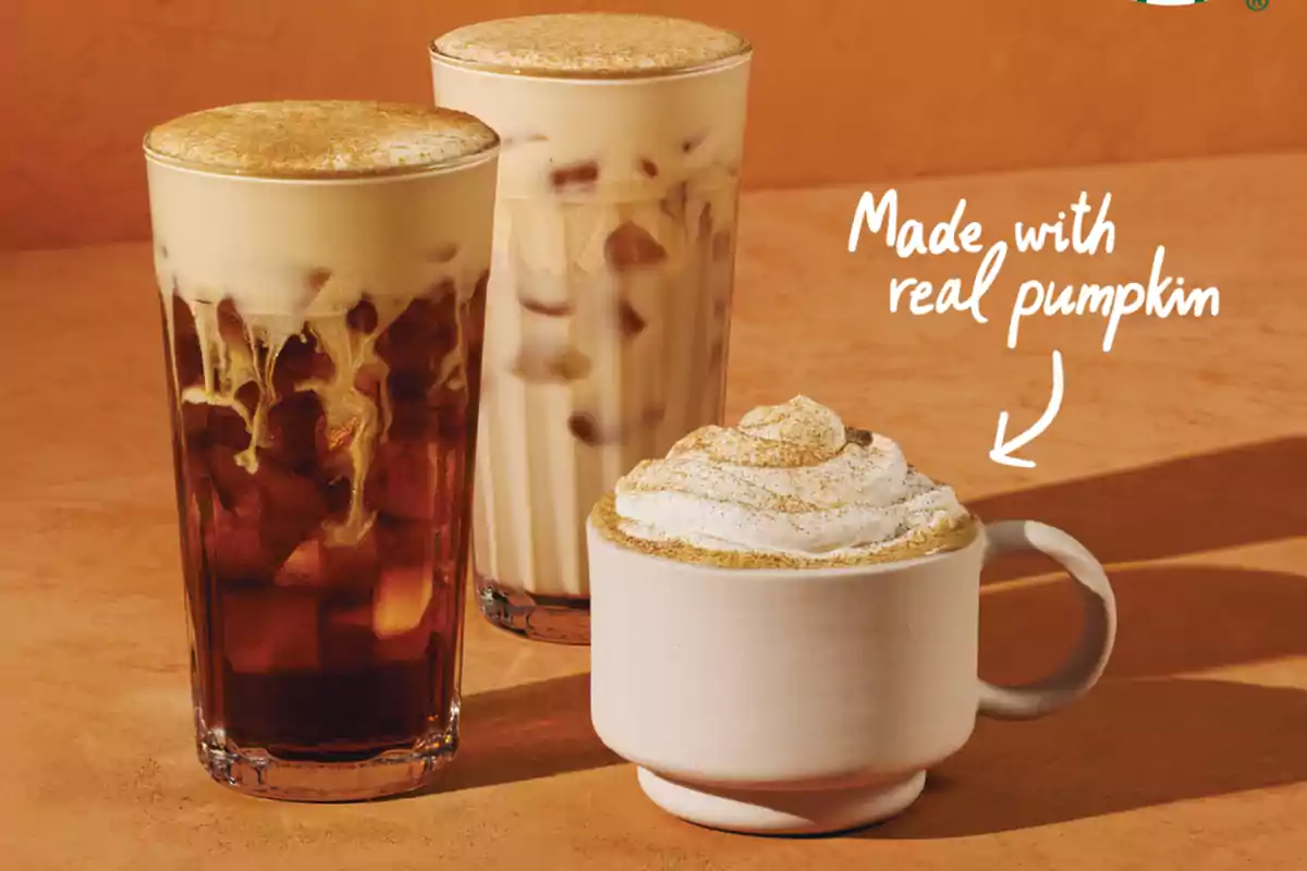 Tres bebidas de café con espuma y crema, una de ellas decorada con crema batida y canela, sobre una mesa color naranja Tres bebidas de café con espuma y crema, una de ellas decorada con crema batida y canela, sobre una mesa color naranja