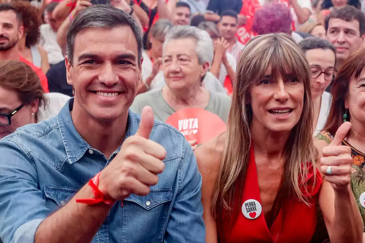 Dos personas sonríen y levantan el pulgar en señal de aprobación en un evento multitudinario rodeados de gente que sostiene carteles y pancartas Dos personas sonríen y levantan el pulgar en señal de aprobación en un evento multitudinario rodeados de gente que sostiene carteles y pancartas