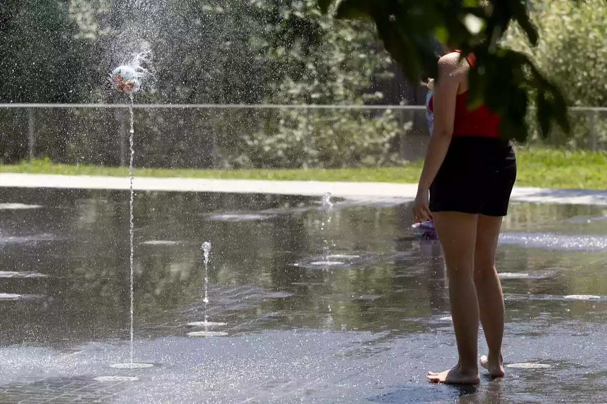 Persona de pie descalza junto a un chorro de agua en una fuente interactiva al aire libre en un día soleado Persona de pie descalza junto a un chorro de agua en una fuente interactiva al aire libre en un día soleado