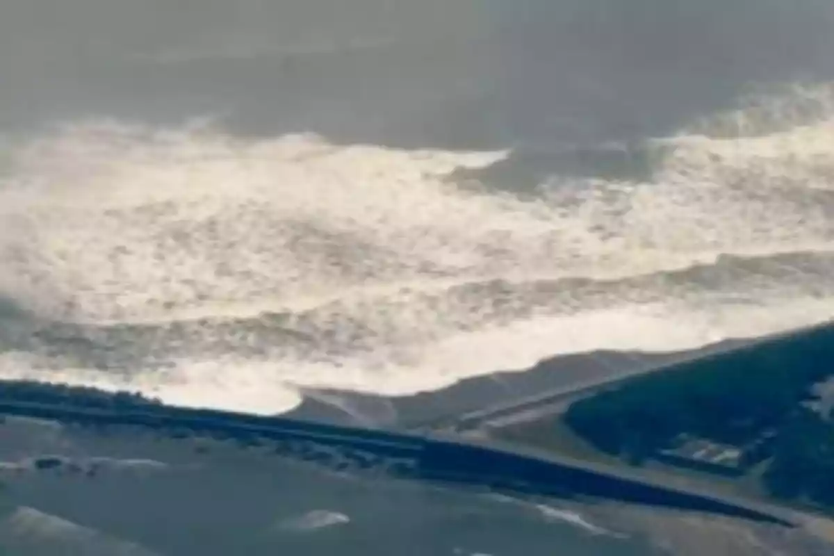 Olas gigantes del mar acercándose a la costa y una carretera visible en primer plano Olas gigantes del mar acercándose a la costa y una carretera visible en primer plano