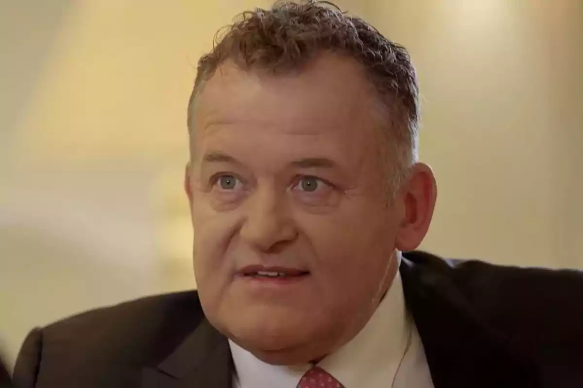 Paul Burrell con traje oscuro y corbata rosa mirando hacia el frente con expresión seria. Captura de 'Viajando con Chester'