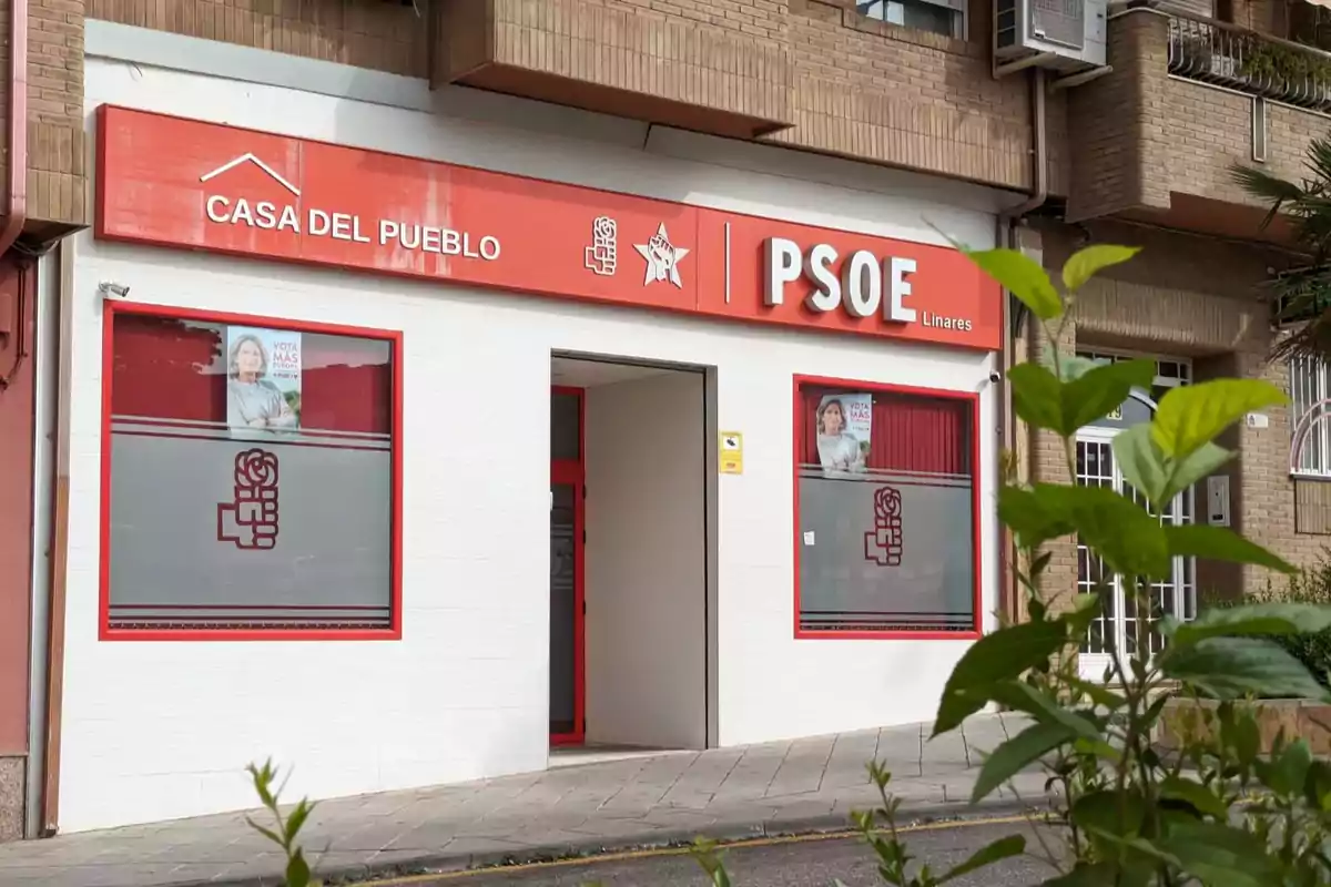 Fachada de una sede del PSOE en Linares con letrero rojo y ventanas decoradas con el logo del partido Fachada de una sede del PSOE en Linares con letrero rojo y ventanas decoradas con el logo del partido