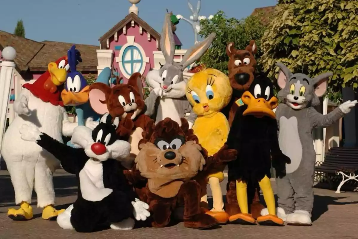 Grupo de personas disfrazadas de personajes animados famosos posando al aire libre frente a una casa colorida