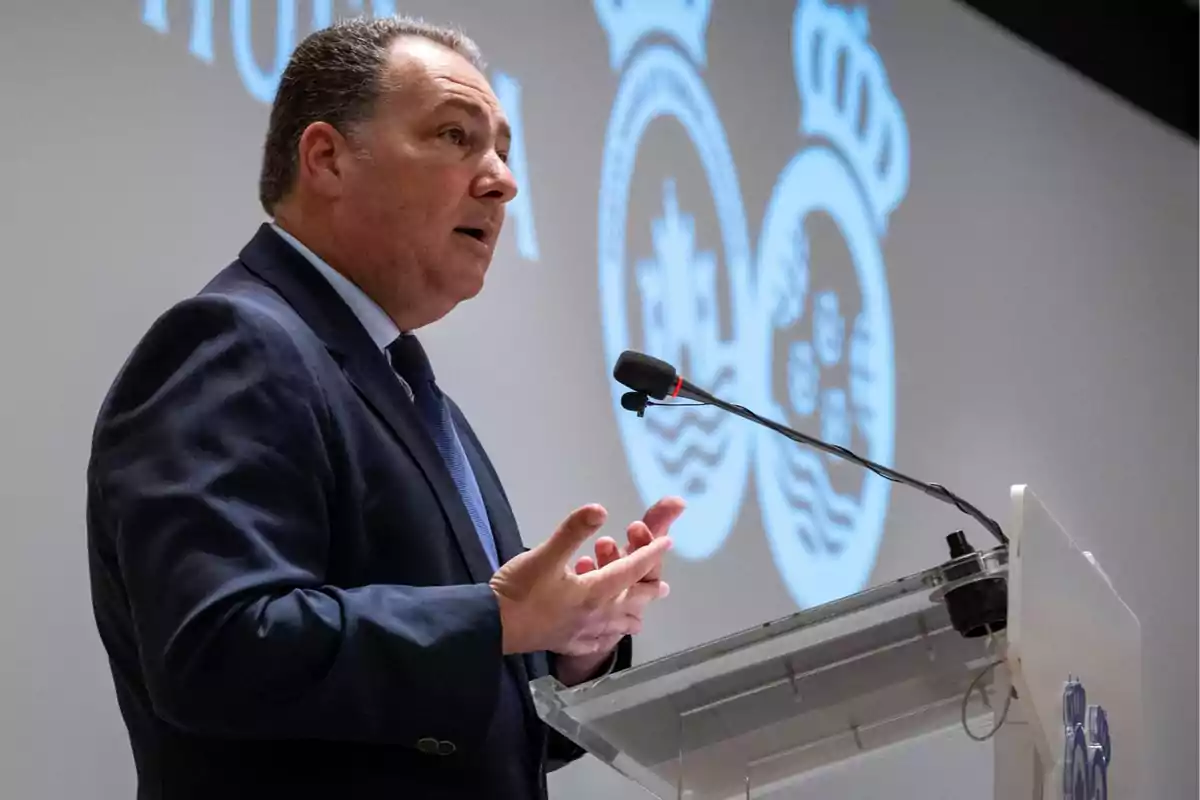 Hombre de traje hablando en un podio con micrófono durante una conferencia o presentación en un auditorio
