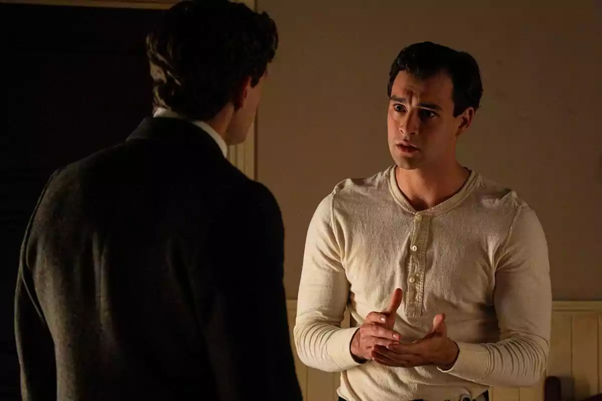 Xavi Lock y Enrique Fortún conversan en una habitación con expresión seria, uno de ellos viste una camiseta clara y gesticula con las manos mientras el otro está de espaldas en La Promesa. Xavi Lock y Enrique Fortún conversan en una habitación con expresión seria, uno de ellos viste una camiseta clara y gesticula con las manos mientras el otro está de espaldas en La Promesa.