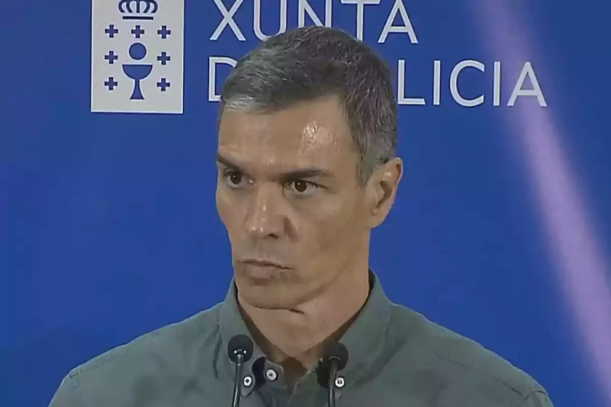 Hombre de cabello corto y canoso hablando frente a micrófonos con un fondo azul que tiene el texto Xunta de Galicia Hombre de cabello corto y canoso hablando frente a micrófonos con un fondo azul que tiene el texto Xunta de Galicia