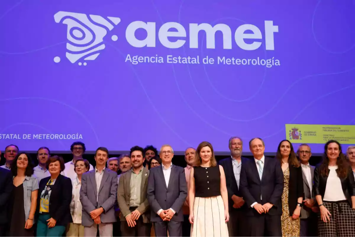 Un grupo de personas posando en un escenario frente a una pantalla grande con el logotipo y nombre de la Agencia Estatal de Meteorología de España Un grupo de personas posando en un escenario frente a una pantalla grande con el logotipo y nombre de la Agencia Estatal de Meteorología de España