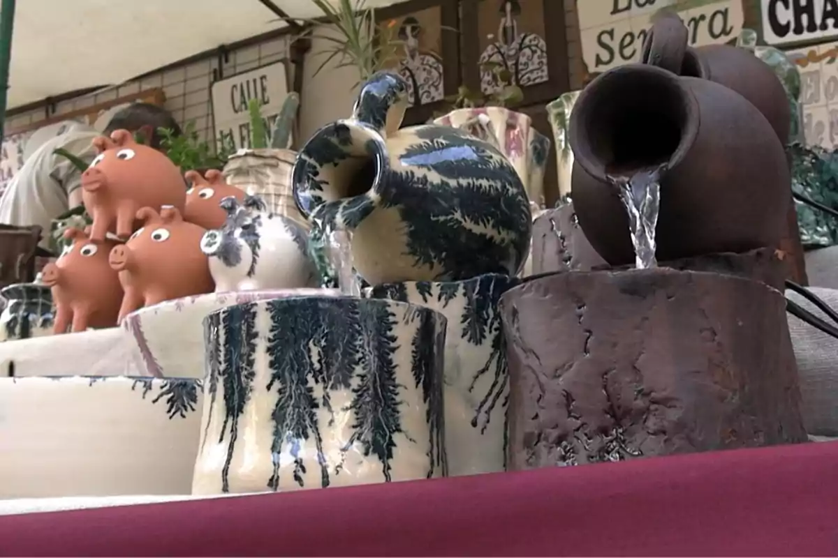 Exhibición de artesanías de cerámica con alcancías en forma de cerdito y jarras decorativas, algunas de las cuales funcionan como fuentes de agua Exhibición de artesanías de cerámica con alcancías en forma de cerdito y jarras decorativas, algunas de las cuales funcionan como fuentes de agua