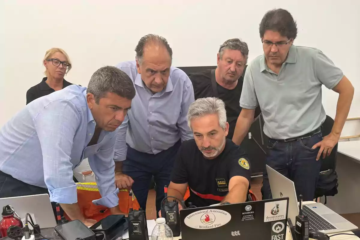 Un grupo de personas observa atentamente la pantalla de una computadora portátil en una oficina, mostrando concentración y trabajo en equipo.