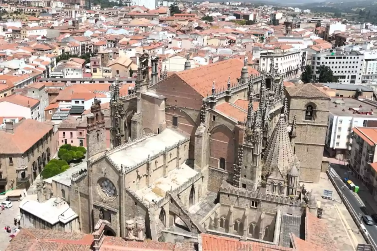 Vista aérea de una catedral gótica rodeada de edificios con techos de tejas rojas en una ciudad Vista aérea de una catedral gótica rodeada de edificios con techos de tejas rojas en una ciudad