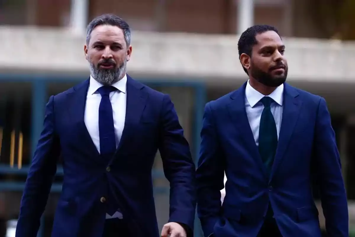 Dos hombres con traje azul caminan juntos en un entorno urbano Dos hombres con traje azul caminan juntos en un entorno urbano