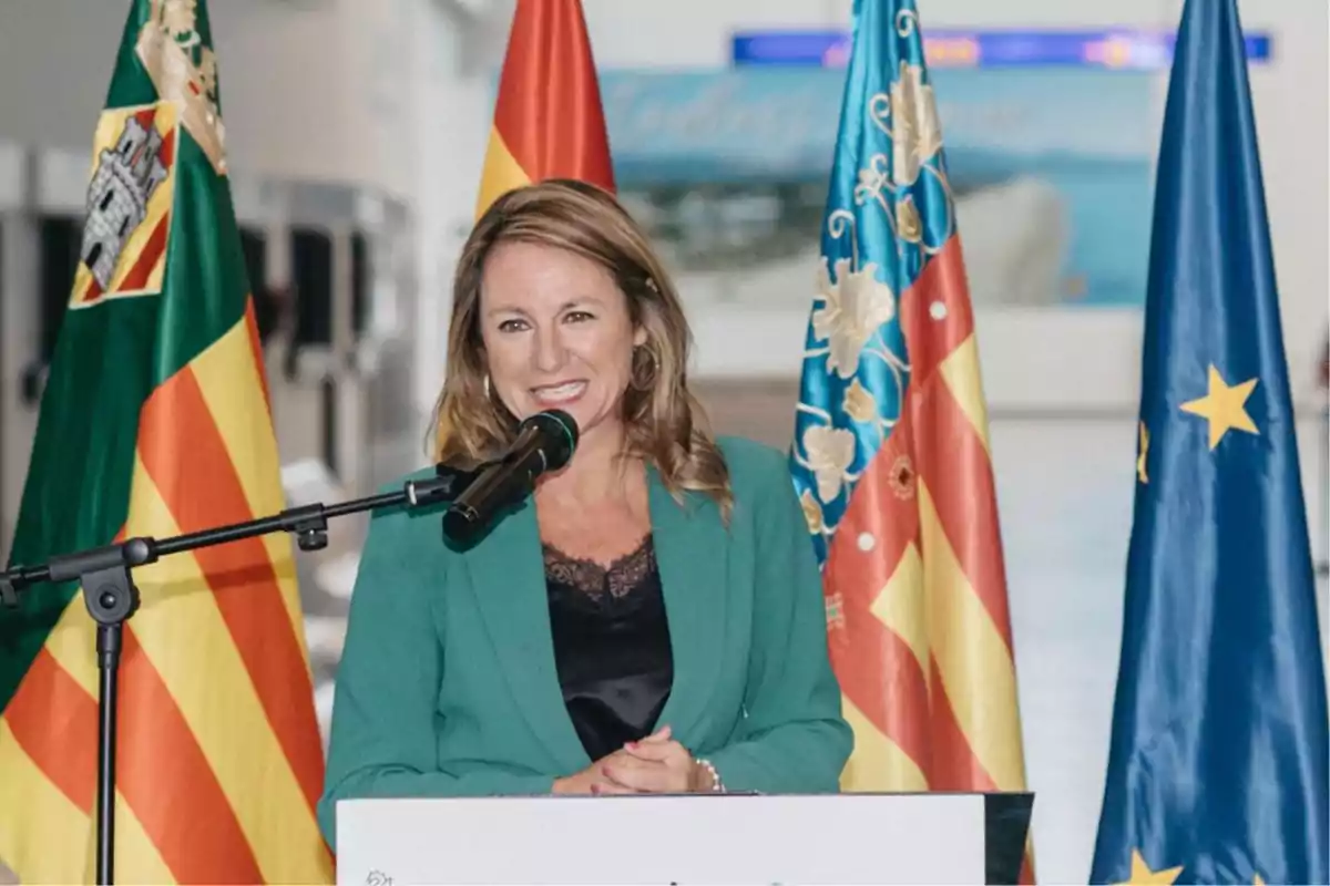 Una mujer hablando en un podio con el sello del Vicepresidente de los Estados Unidos mientras un hombre la observa en el fondo. Una mujer hablando en un podio con el sello del Vicepresidente de los Estados Unidos mientras un hombre la observa en el fondo.