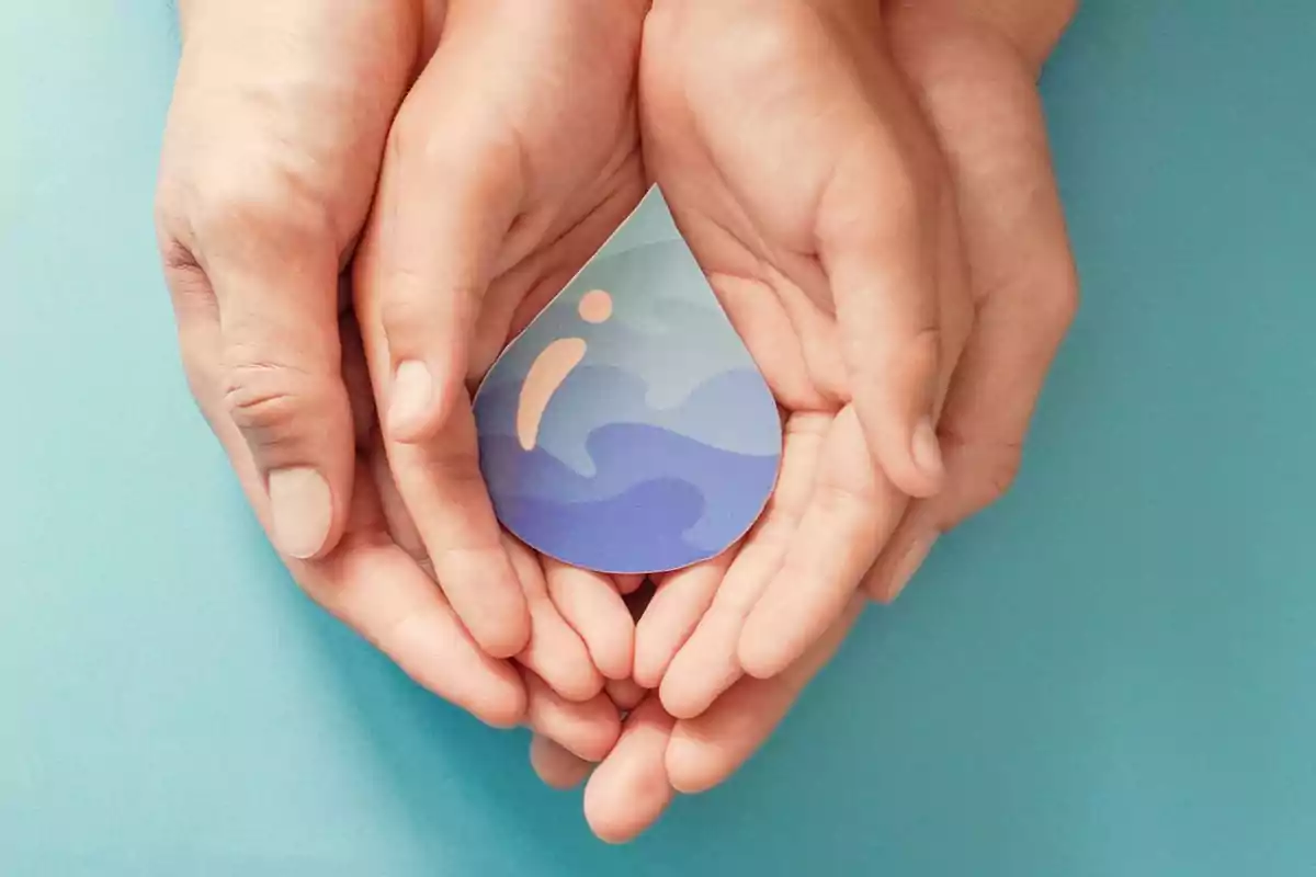 Manos sosteniendo una gota de papel con diseño de agua sobre fondo azul