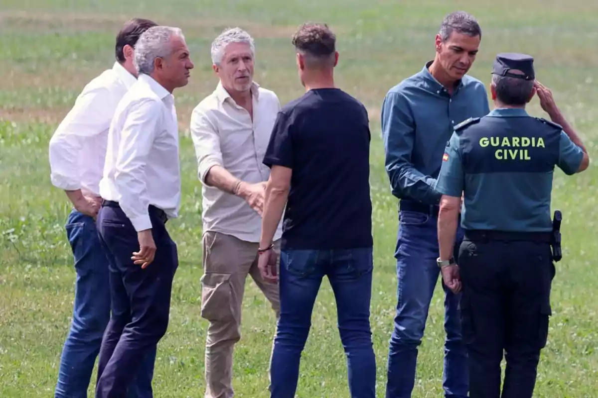 Un grupo de hombres conversa al aire libre mientras un agente de la Guardia Civil saluda Un grupo de hombres conversa al aire libre mientras un agente de la Guardia Civil saluda