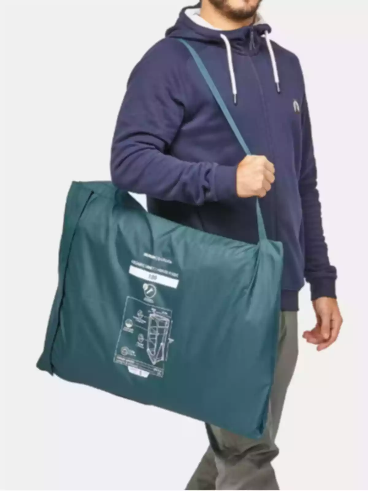 Hombre con sudadera azul lleva una bolsa grande de color verde en el hombro Hombre con sudadera azul lleva una bolsa grande de color verde en el hombro