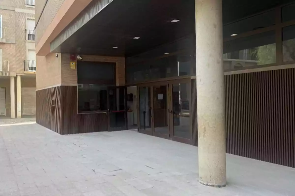 Entrada de un edificio moderno con paredes de ladrillo, puertas de cristal y una columna grande en primer plano Entrada de un edificio moderno con paredes de ladrillo, puertas de cristal y una columna grande en primer plano