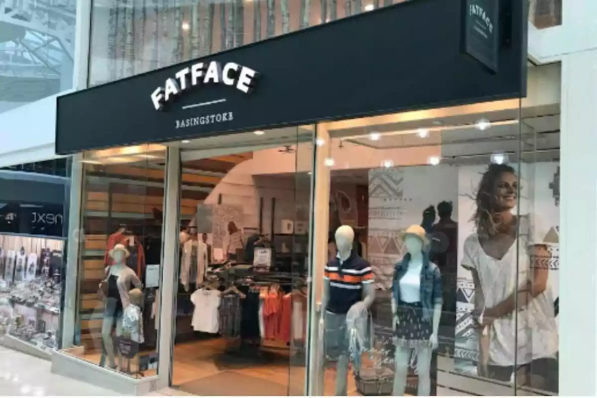 Storefront of a clothing shop called FatFace with mannequins in the window display and a large poster of a smiling woman inside Storefront of a clothing shop called FatFace with mannequins in the window display and a large poster of a smiling woman inside