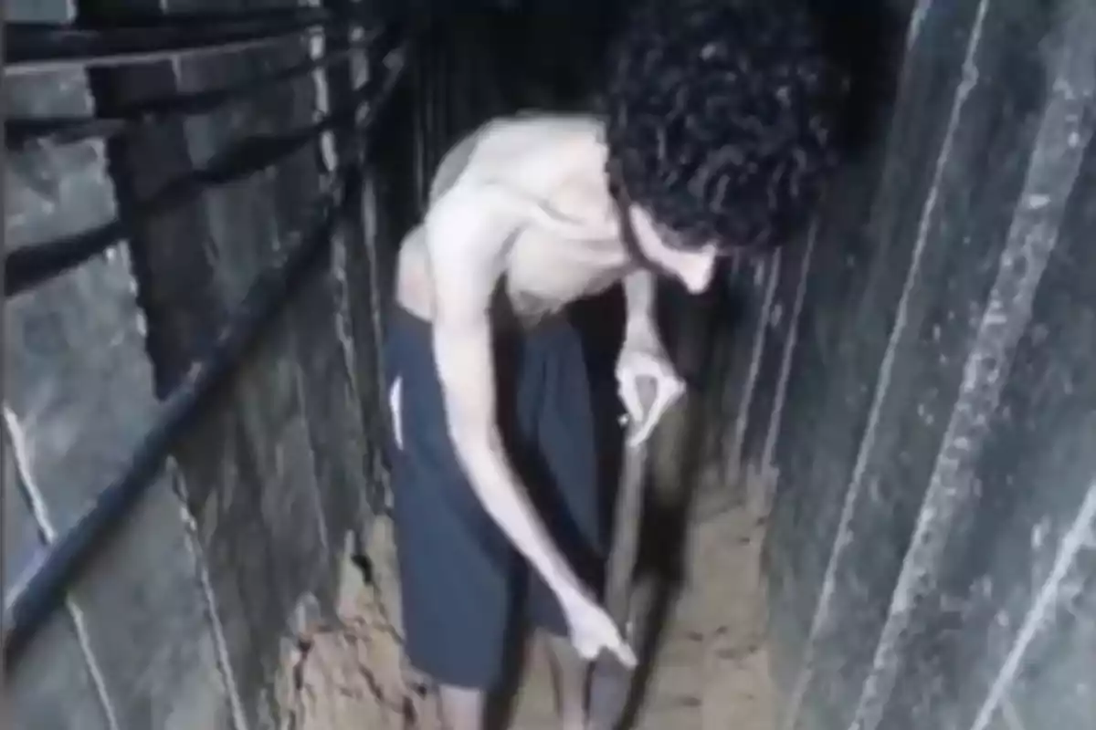Hombre sin camisa cavando en un túnel subterráneo con paredes de madera Hombre sin camisa cavando en un túnel subterráneo con paredes de madera