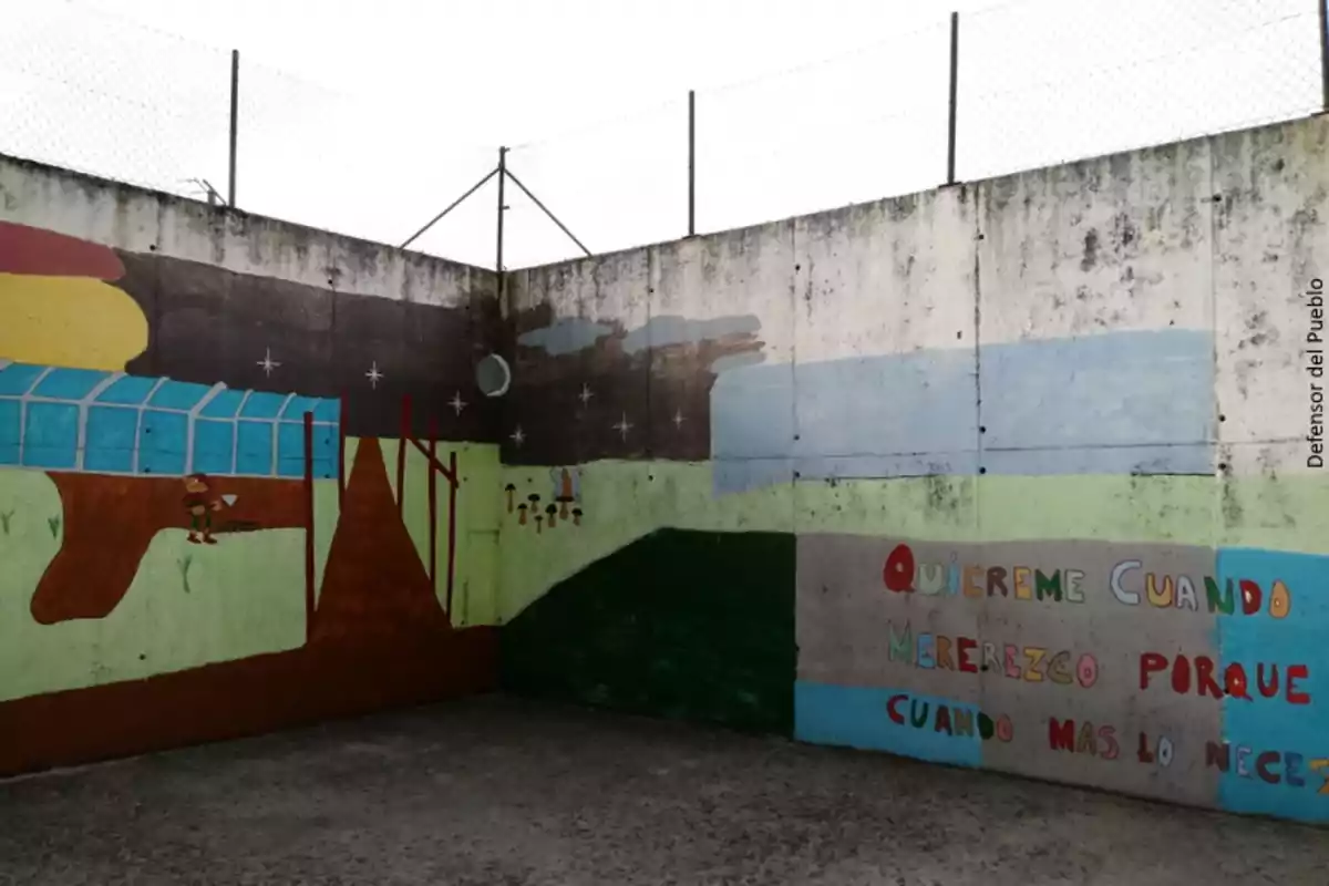 Mural pintado en la pared de un patio con dibujos de un paisaje, un niño y un mensaje colorido que dice quiéreme cuando me lo merezco porque es cuando más lo necesito Mural pintado en la pared de un patio con dibujos de un paisaje, un niño y un mensaje colorido que dice quiéreme cuando me lo merezco porque es cuando más lo necesito