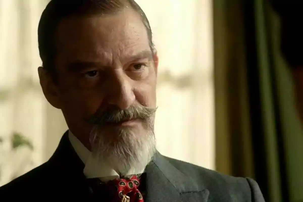 Alfonso Mendiguchía con bigote y barba canosa vestido con traje oscuro y corbata roja mirando con expresión seria. Alfonso Mendiguchía con bigote y barba canosa vestido con traje oscuro y corbata roja mirando con expresión seria.