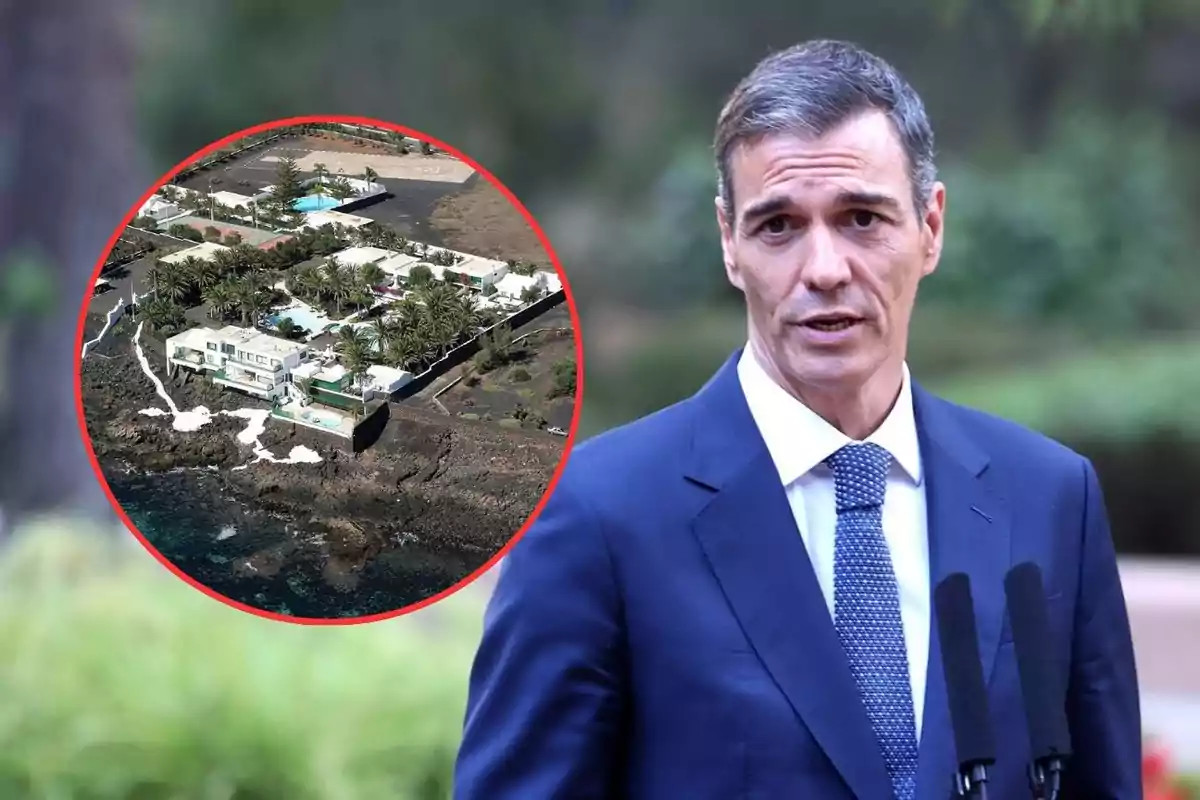 Hombre con traje azul hablando frente a micrófonos y al fondo un círculo muestra una vista aérea de un complejo de casas junto al mar rodeado de vegetación