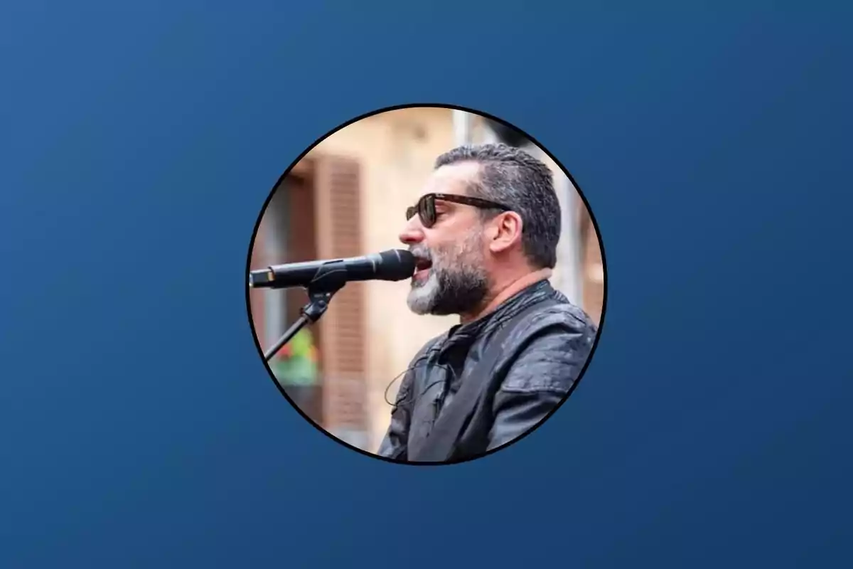Hombre con barba y gafas de sol cantando frente a un micrófono