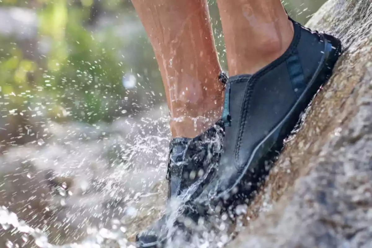 Persona usando zapatos impermeables mientras camina sobre una superficie mojada con salpicaduras de agua Persona usando zapatos impermeables mientras camina sobre una superficie mojada con salpicaduras de agua