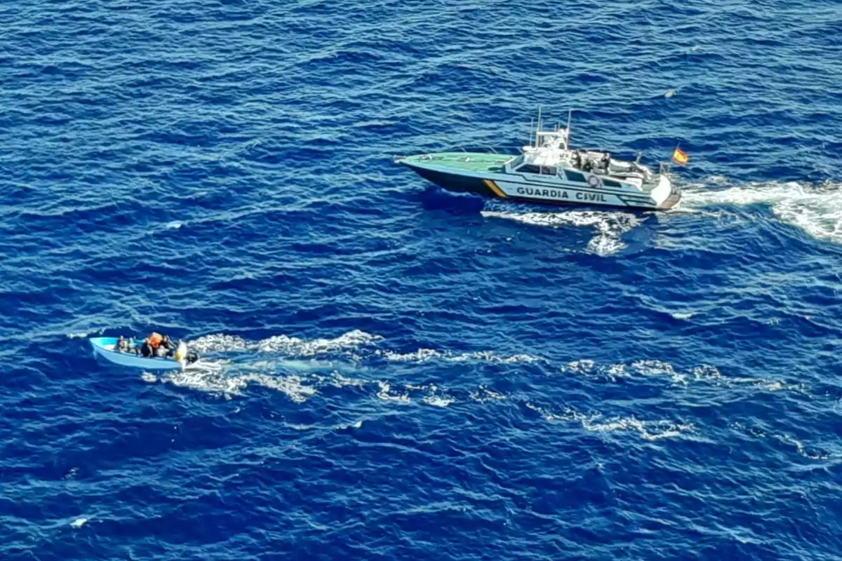 Una lancha de la Guardia Civil persigue a una pequeña embarcación azul con varias personas a bordo en mar abierto Una lancha de la Guardia Civil persigue a una pequeña embarcación azul con varias personas a bordo en mar abierto