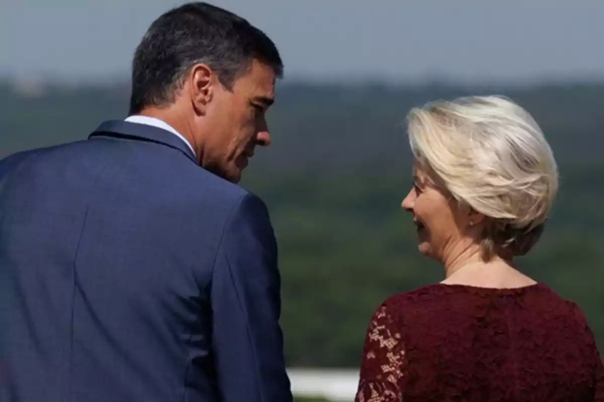 Dos personas elegantemente vestidas conversan al aire libre con un paisaje natural de fondo Dos personas elegantemente vestidas conversan al aire libre con un paisaje natural de fondo