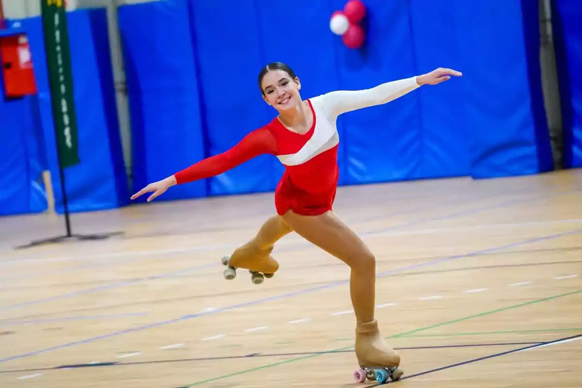 Joven patinadora artística sobre ruedas realizando una pose elegante en una pista cubierta Joven patinadora artística sobre ruedas realizando una pose elegante en una pista cubierta