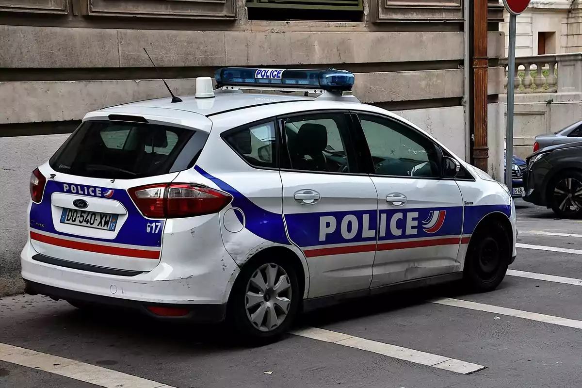 Coche patrulla de la policía francesa estacionado junto a una acera en una calle urbana Coche patrulla de la policía francesa estacionado junto a una acera en una calle urbana