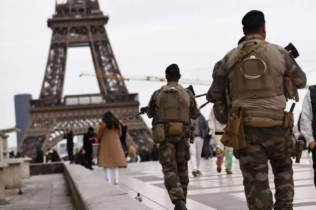 Soldados patrullan una zona turística cerca de la Torre Eiffel en París mientras varias personas caminan por el lugar Soldados patrullan una zona turística cerca de la Torre Eiffel en París mientras varias personas caminan por el lugar