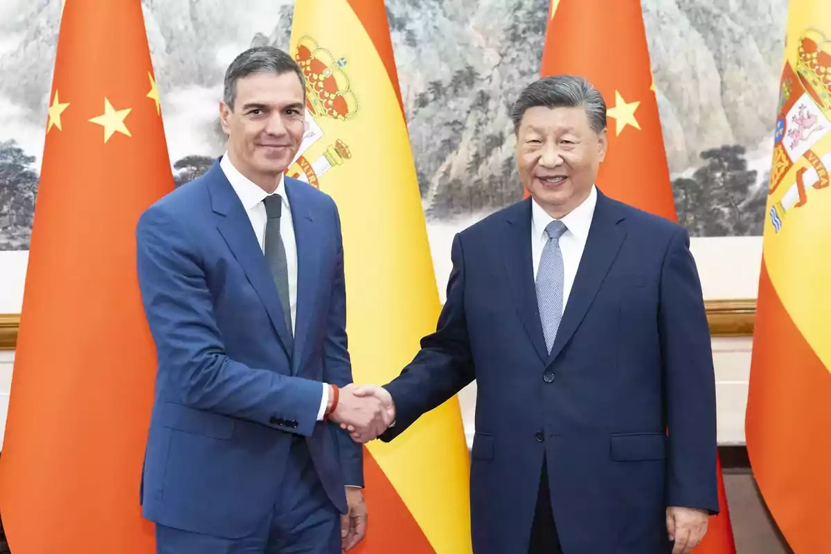 Dos hombres con traje se dan la mano frente a las banderas de China y España Dos hombres con traje se dan la mano frente a las banderas de China y España