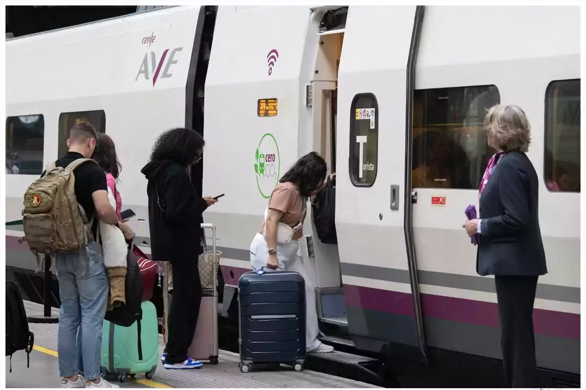 Personas subiendo a un tren de alta velocidad AVE con maletas en una estación mientras una empleada observa