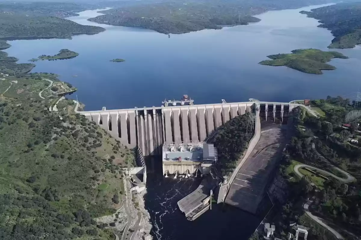 Vista aérea de una gran presa rodeada de vegetación y un extenso embalse de agua Vista aérea de una gran presa rodeada de vegetación y un extenso embalse de agua