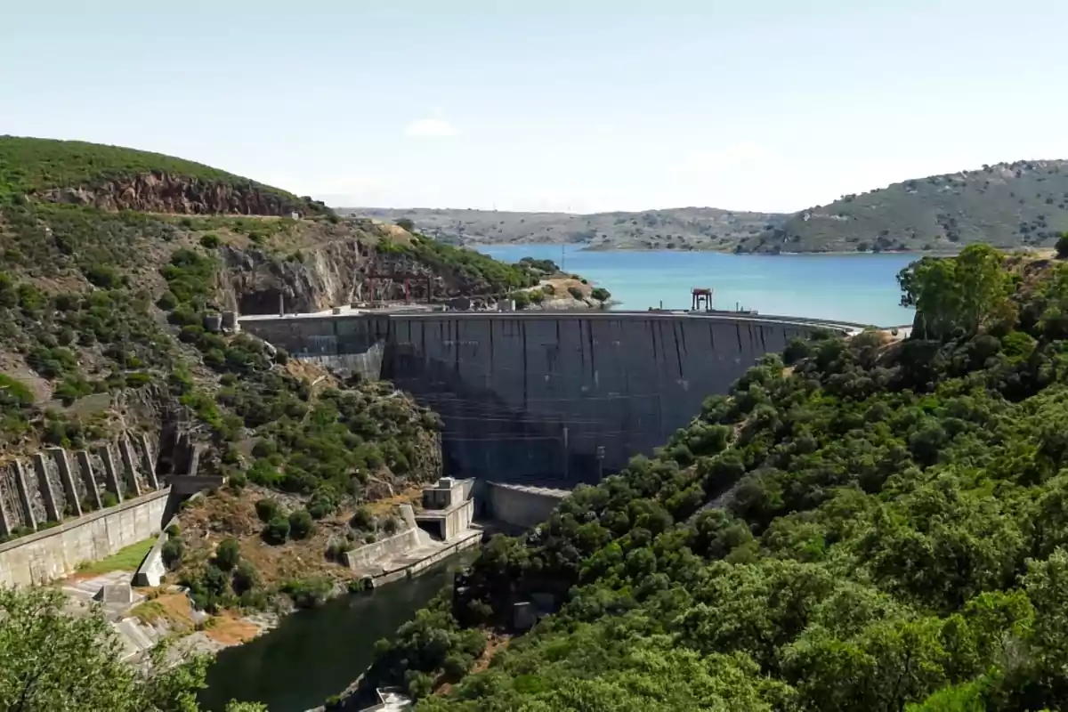 Vista panorámica de una presa rodeada de colinas verdes y un embalse de agua azul al fondo