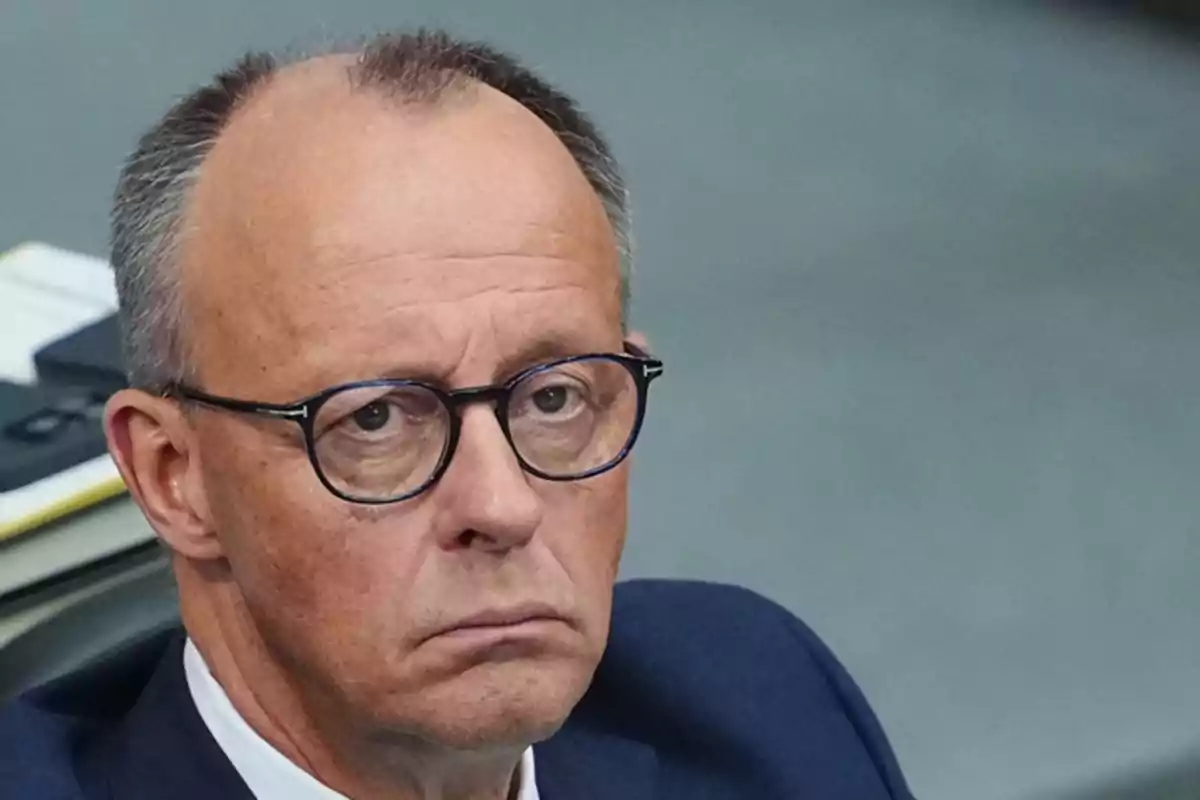 Hombre de mediana edad con gafas y expresión seria vestido con traje oscuro Hombre de mediana edad con gafas y expresión seria vestido con traje oscuro