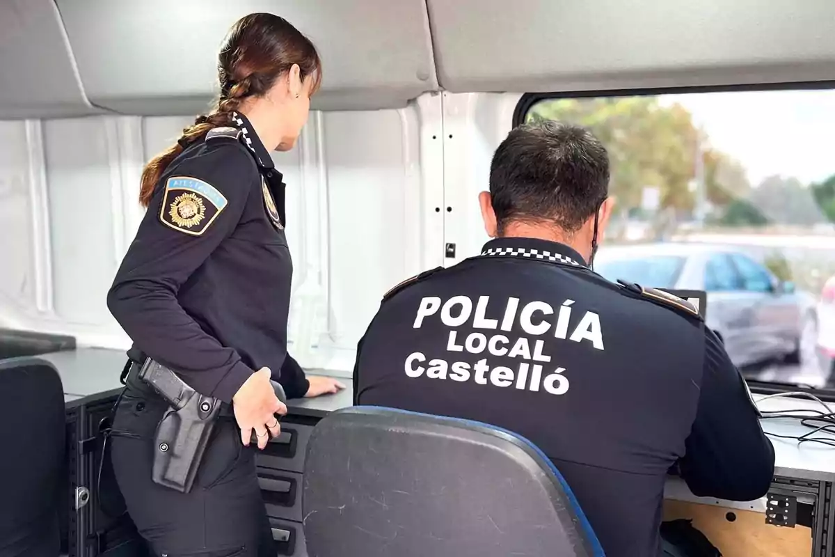 Dos agentes de la policía local de Castelló trabajan en el interior de una unidad móvil mientras observan una pantalla Dos agentes de la policía local de Castelló trabajan en el interior de una unidad móvil mientras observan una pantalla