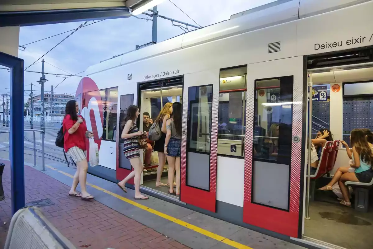 Personas subiendo y bajando de un tranvía moderno en una estación urbana al atardecer