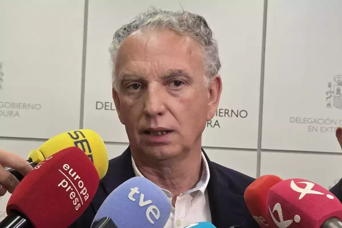 Un hombre de cabello canoso y expresión seria responde preguntas de varios medios de comunicación frente a micrófonos de diferentes colores en una rueda de prensa Un hombre de cabello canoso y expresión seria responde preguntas de varios medios de comunicación frente a micrófonos de diferentes colores en una rueda de prensa