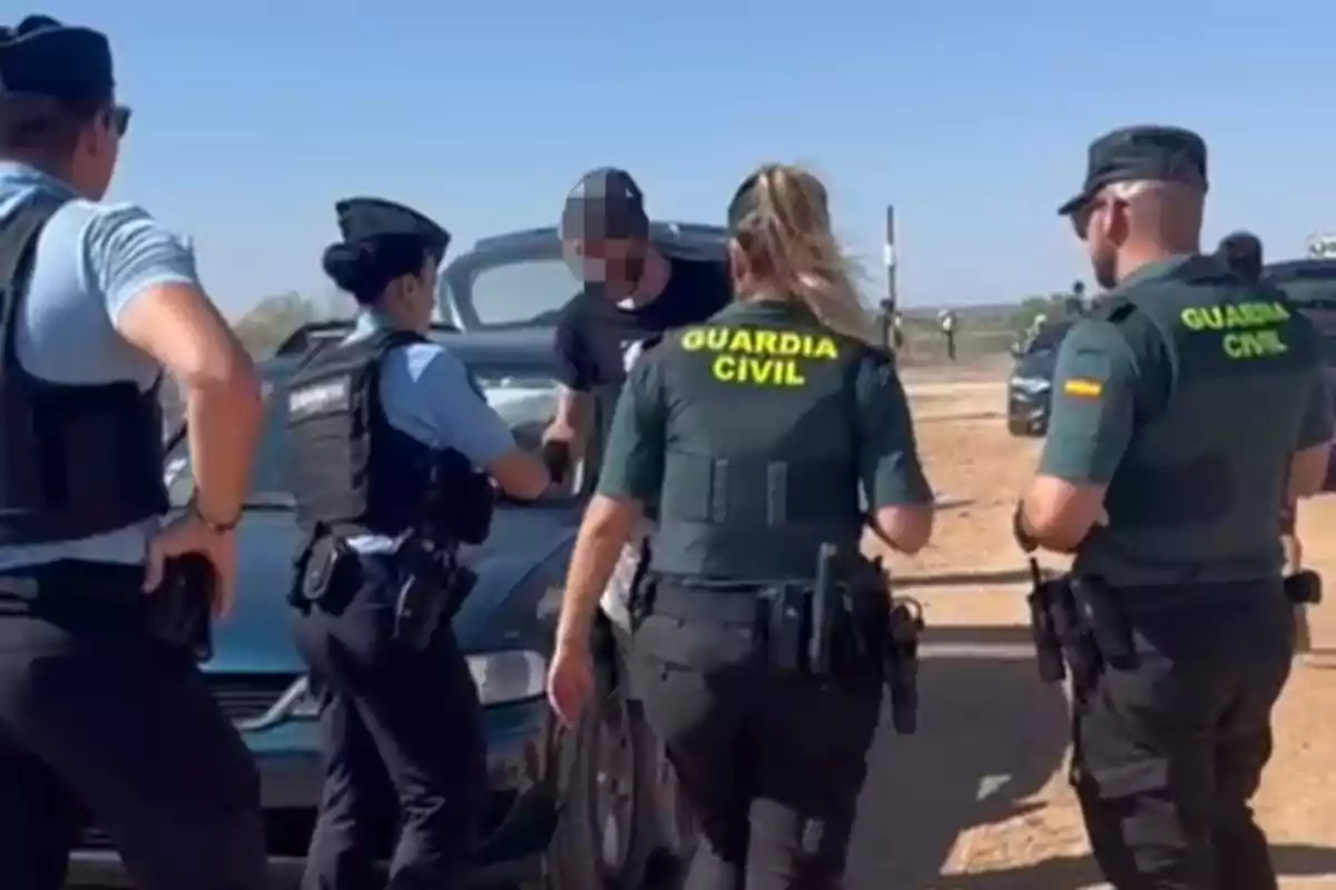 Varios agentes de la Guardia Civil y la policía detienen a una persona junto a un coche en un camino de tierra durante el día. Varios agentes de la Guardia Civil y la policía detienen a una persona junto a un coche en un camino de tierra durante el día.