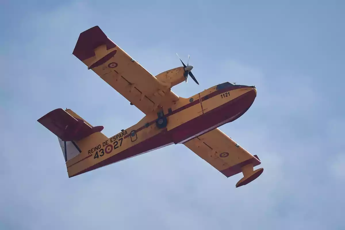 Avión amarillo y rojo de extinción de incendios volando en el cielo con la inscripción Reino de España en el fuselaje Avión amarillo y rojo de extinción de incendios volando en el cielo con la inscripción Reino de España en el fuselaje