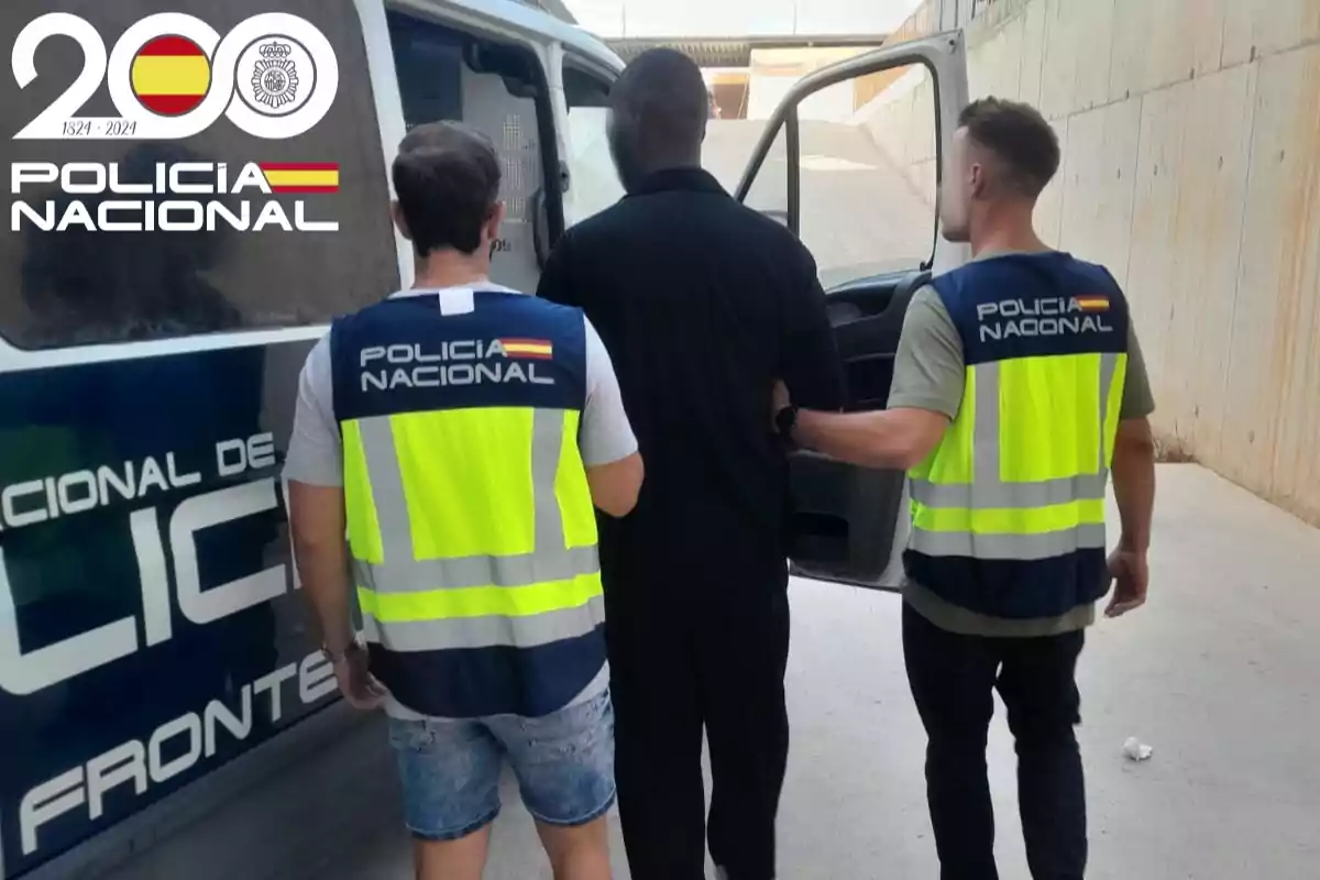 Dos agentes de la Policía Nacional escoltan a una persona hacia una furgoneta policial en un entorno urbano, ambos llevan chalecos reflectantes y el logo del bicentenario de la Policía Nacional aparece en la esquina superior izquierda Dos agentes de la Policía Nacional escoltan a una persona hacia una furgoneta policial en un entorno urbano, ambos llevan chalecos reflectantes y el logo del bicentenario de la Policía Nacional aparece en la esquina superior izquierda