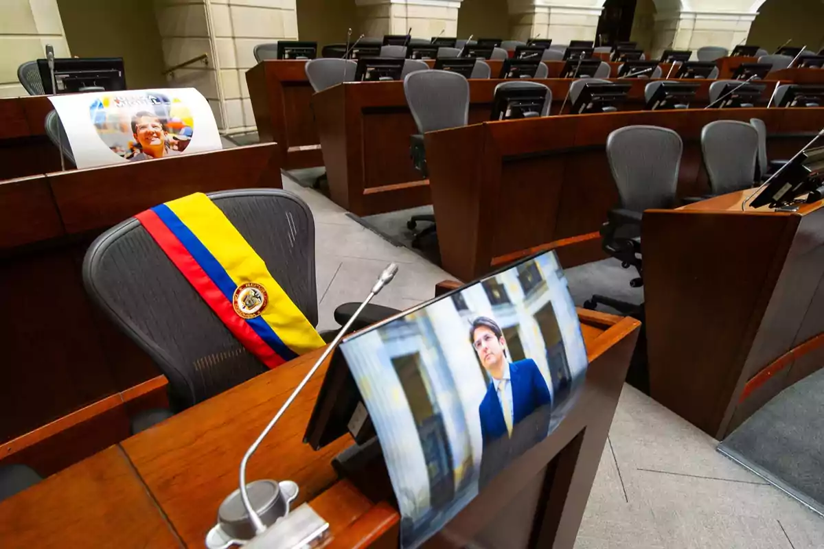Silla vacía en un recinto legislativo con una banda de Colombia y una fotografía de una persona sobre el escritorio