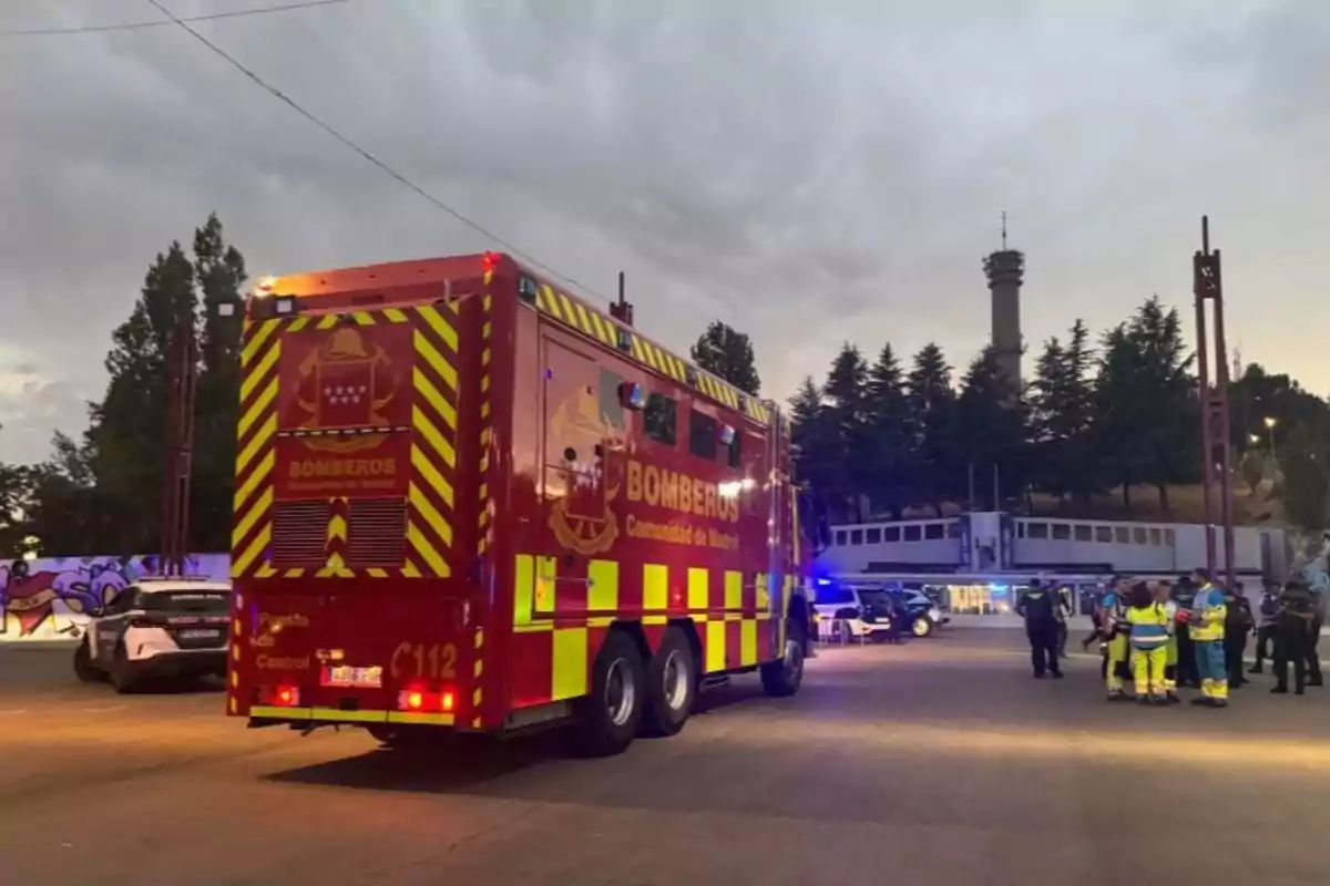 Camión de bomberos de la Comunidad de Madrid estacionado en una calle al atardecer con varios equipos de emergencia y policías reunidos cerca Camión de bomberos de la Comunidad de Madrid estacionado en una calle al atardecer con varios equipos de emergencia y policías reunidos cerca