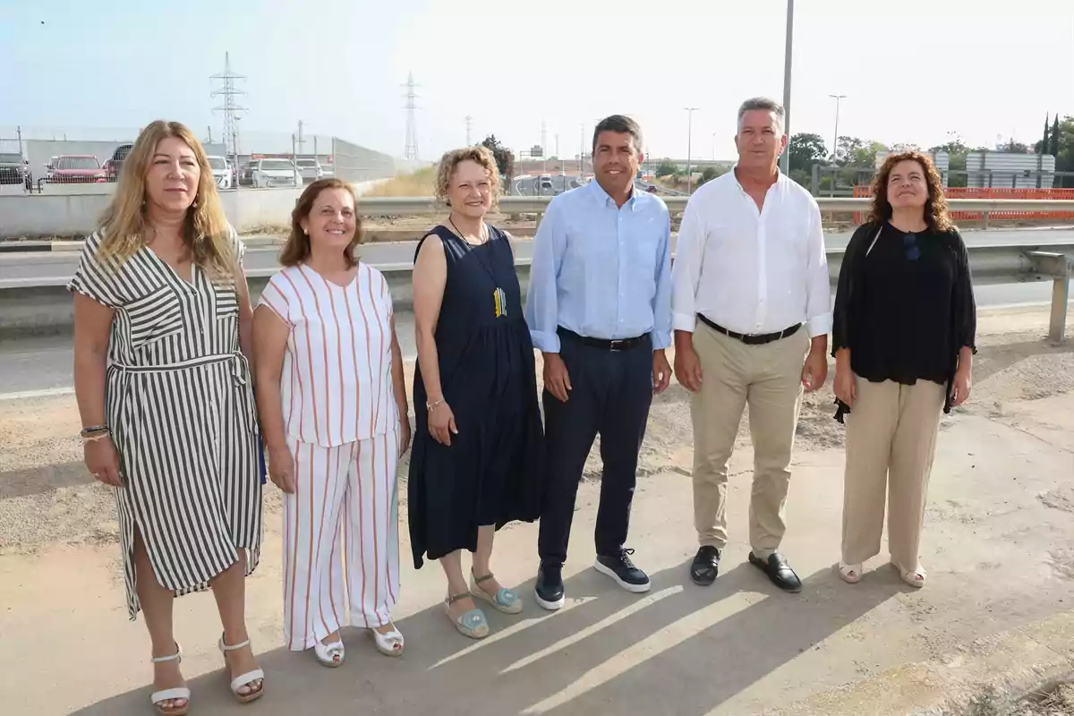 Seis personas posan de pie al aire libre junto a una carretera en un día soleado Seis personas posan de pie al aire libre junto a una carretera en un día soleado