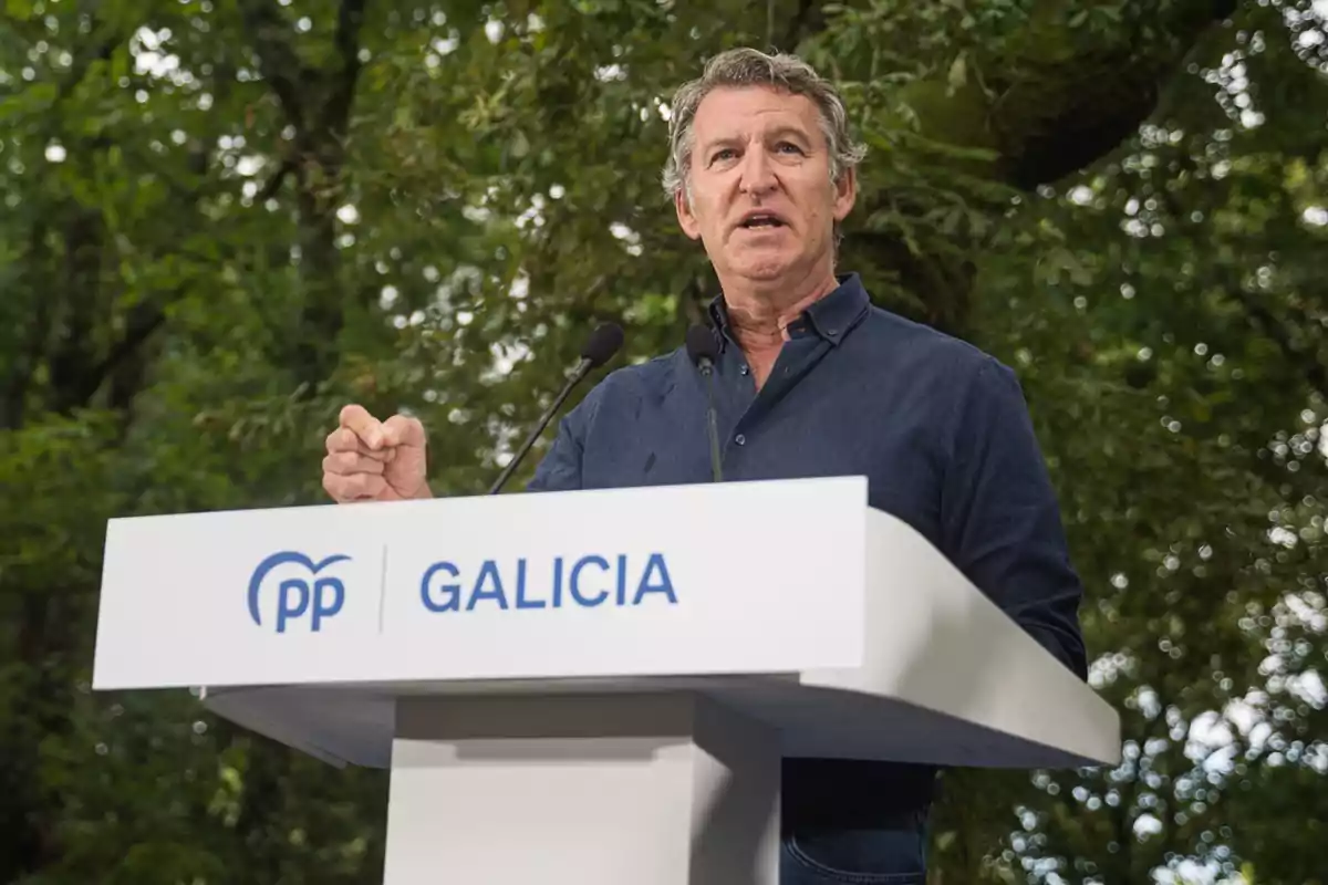 Hombre hablando en un atril del Partido Popular de Galicia en un entorno al aire libre con árboles de fondo Hombre hablando en un atril del Partido Popular de Galicia en un entorno al aire libre con árboles de fondo