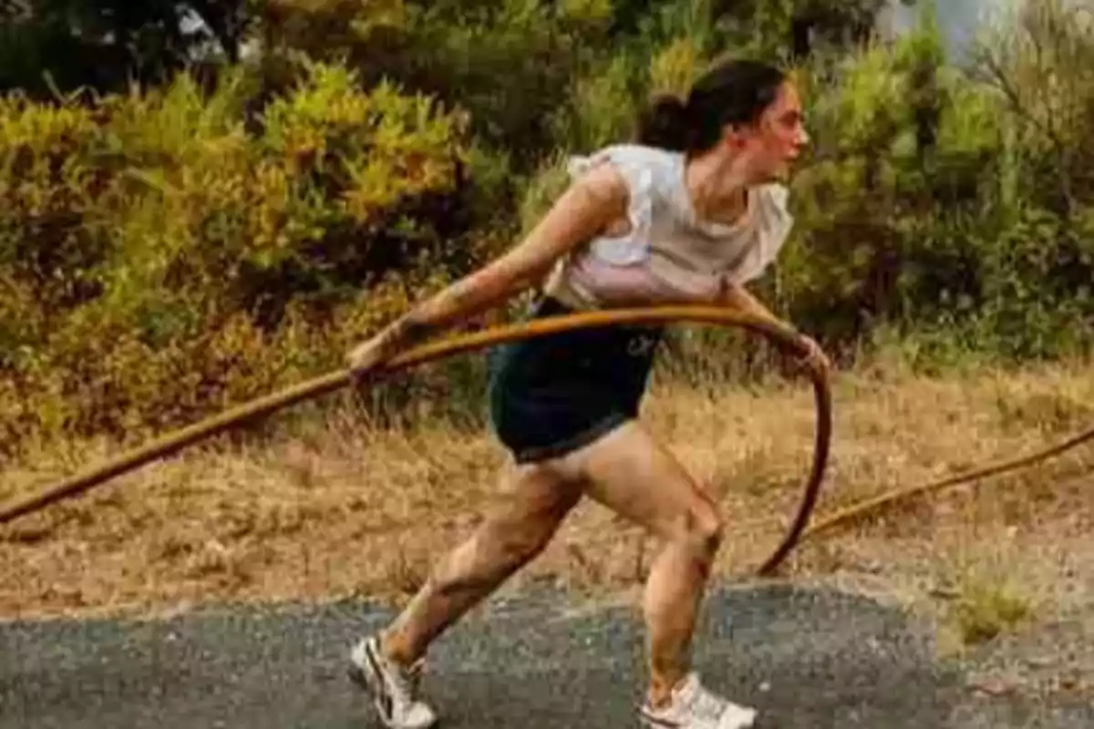 Mujer con ropa deportiva y manguera corriendo sobre un camino rodeado de vegetación Mujer con ropa deportiva y manguera corriendo sobre un camino rodeado de vegetación